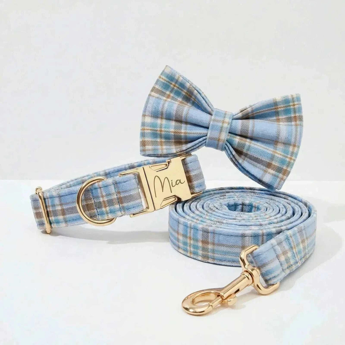 personalized no pull dog harness set in light blue plaid, showing a gold nameplate collar, rolled leash, and matching bow tie